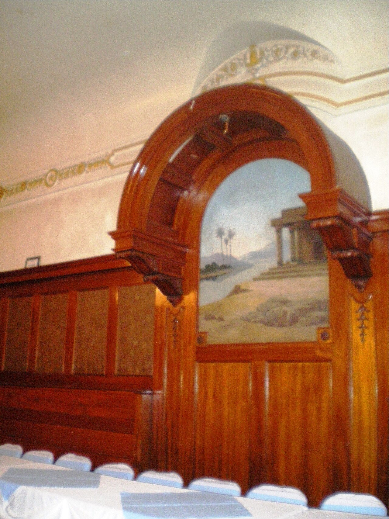 A traditional Masonic Lodge room with officer chairs, altar, and chequered pavement